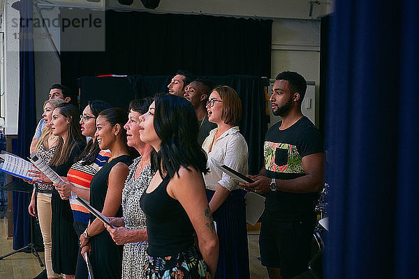 Multi-ethnische Gruppe von Schülern  die im Chor in der Schulaula singen