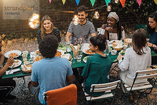 Schrägaufnahme von multi-ethnischen jungen Freunden  die während einer Gartenparty am Tisch zu Abend essen