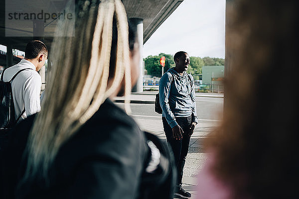 Freunde schauen lächelnden Mann an  der in der Stadt auf der Straße steht