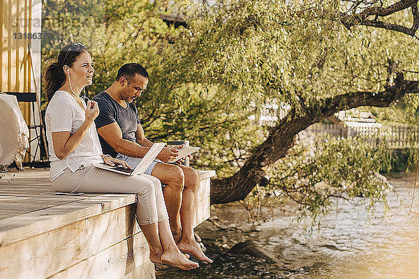 Reifes Paar benutzt Laptops  während es auf der Terrasse einer Ferienvilla sitzt