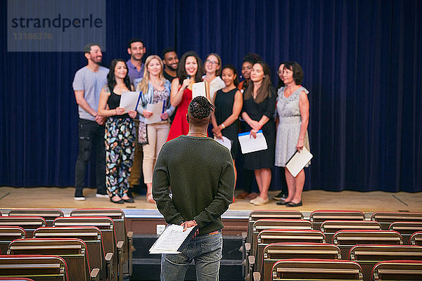 Musiklehrer hört den Chor auf der Bühne in der Aula der Sprachschule