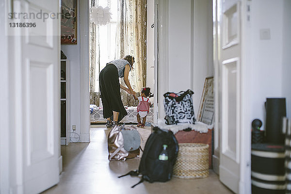 Mutter  die ihrer Tochter beim Gehen hilft  zu Hause durch die Tür gesehen