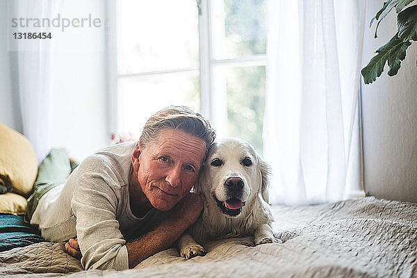 Nahaufnahme-Porträt eines älteren Mannes und eines Hundes  die zu Hause auf dem Bett liegen