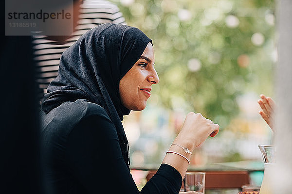 Junge Frau im Hidschab schaut weg  während sie während der Party auf dem Balkon sitzt