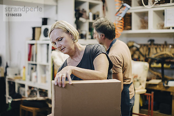 Handwerkerin mit Pappkarton in der Werkstatt