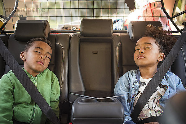 Müde Geschwister schlafen im Elektroauto