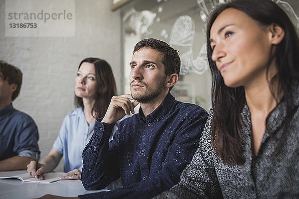 Kreative Geschäftsleute hören zu  während sie während einer Sitzung im Sitzungssaal sitzen