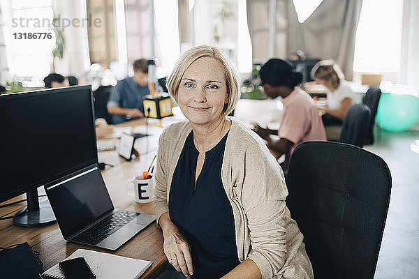 Porträt einer selbstbewussten reifen Geschäftsfrau  die am Computerschreibtisch im Kreativbüro sitzt