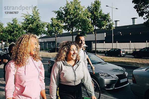 Fröhliche Freunde gehen in der Stadt mit dem Auto auf der Straße