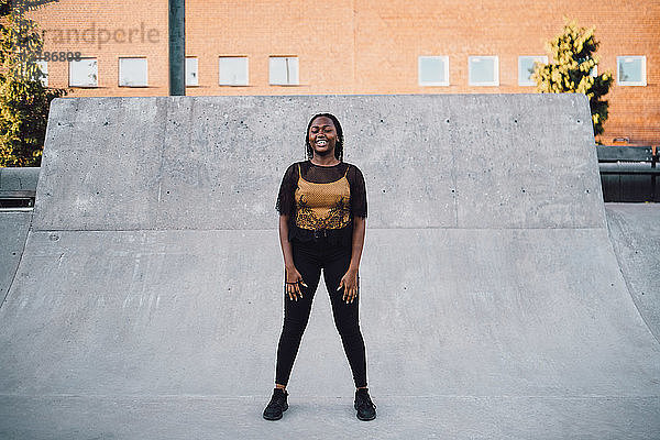 Lächelndes Teenager-Mädchen tanzt in voller Länge im Skateboard-Park