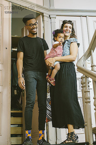 Glückliche Mutter und Vater mit Tochter am Eingang in Wohnung