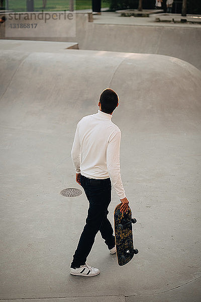 Hochwinkelaufnahme eines Mannes mit Skateboard beim Gehen im Park