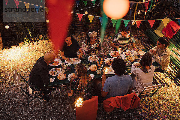 Schrägansicht auf multi-ethnische Freunde beim Abendessen während einer Gartenparty im Garten