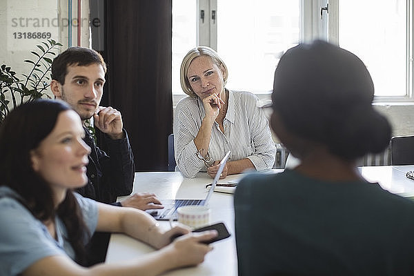 Unternehmer  die einer Kollegin während einer Sitzung im Sitzungssaal zuhören