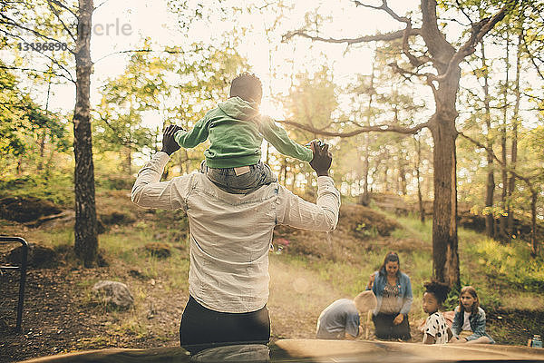 Mann trägt die Schultern seines Sohnes während eines Picknicks mit der Familie im öffentlichen Park