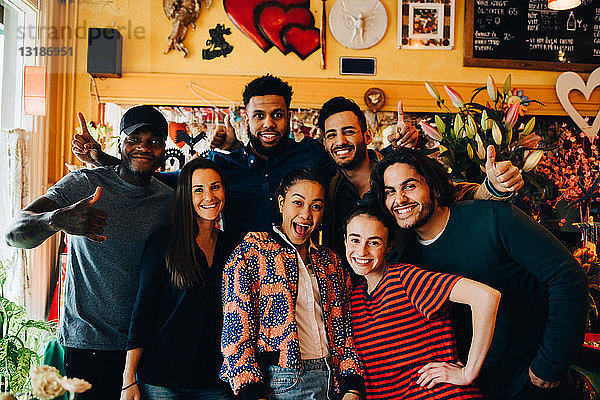 Porträt fröhlicher junger multi-ethnischer Freunde beim Stehen im Restaurant während des Brunch