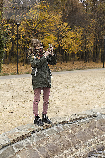 Tween Mädchen mit Kamera-Handy im Herbst Park