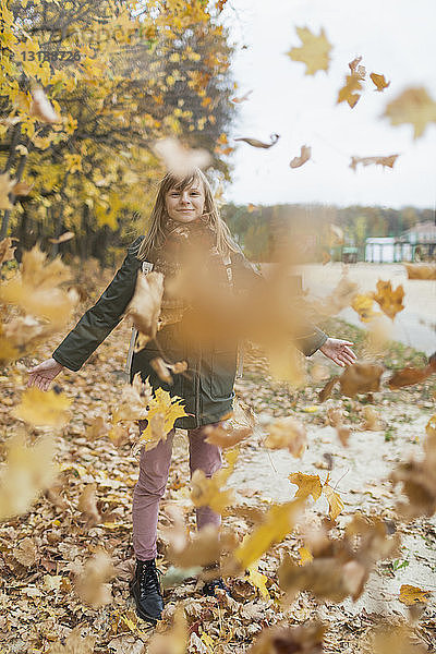 Playful tween Mädchen spielen im Herbst Blätter im Park