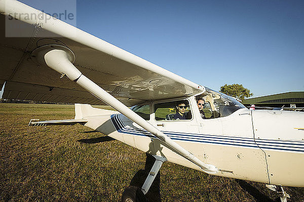 Vater und Sohn in einem kleinen Flugzeug auf einem sonnigen Feld