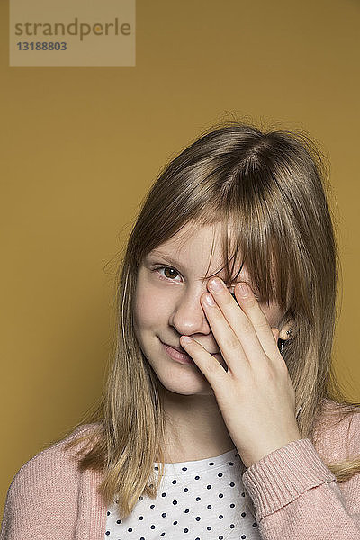 Porträt lächelnd tween Mädchen bedeckt Auge mit der Hand