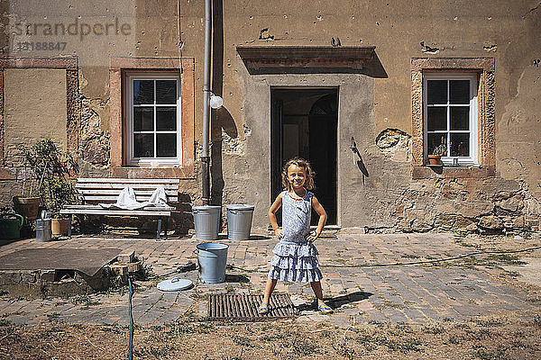 Porträt selbstbewusstes Mädchen vor sonnigem Bauernhaus stehend