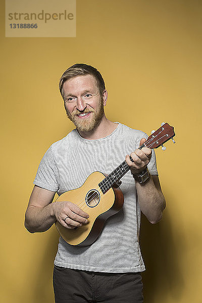 Portrait lächelnder Mann spielt Ukulele