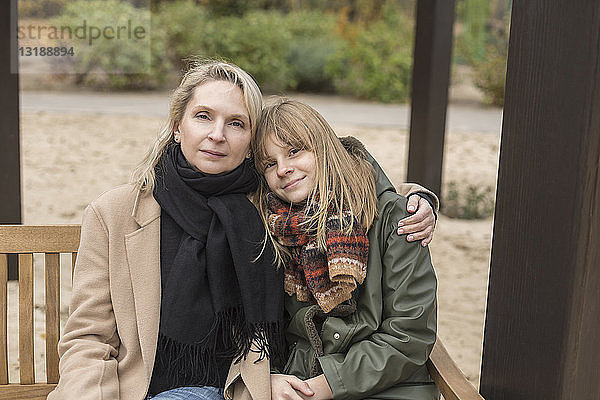Porträt liebevolle Mutter und Tochter  die sich auf einer Parkbank umarmen