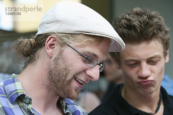 Zwei junge Männer  die in einem Buch blättern und sich über den lustigen Inhalt amüsieren  Deutschland  Europa