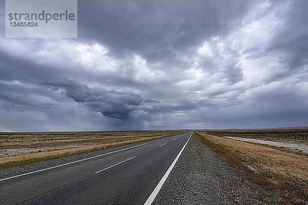 Straße mit Gewitterstimmung durch die Pampa von Patagonien  nahe Rio Gallegos  Argentinien  Südamerika