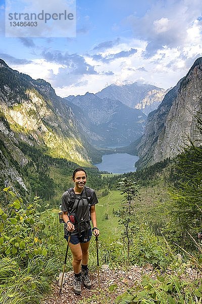Junge Frau posiert mit WanderstÃ¶cken  Wandern  Bergsteigen  Blick vom Rothsteig zum Obersee  KÃ¶nigsee  Alpen  Berglandschaft  Nationalpark Berchtesgaden  Berchtesgadener Land  Oberbayern  Bayern  Deutschland  Europa