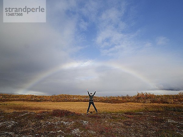 Frau springt in die Luft unter Regenbogen  Herbstlandschaft  Norrbotten  Kreis Norrbotten  Lappland  Lappland  Schweden  Europa
