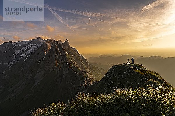 Fotograf auf grasbewachsenem Grat bei Sonnenuntergang mit dem SÃ¤ntis-Gipfel im Hintergrund  Wasserauen  Appenzell  Schweiz  Europa
