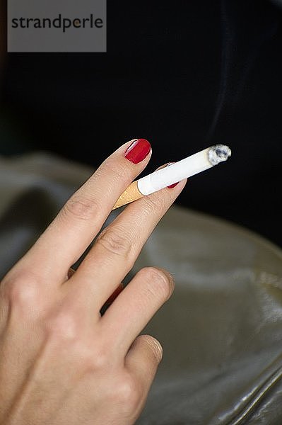 Hand einer jungen Frau  die eine Zigarette hält