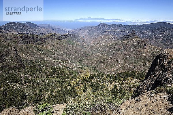 Blick vom Roque Nublo  Kultfelsen der Altkanarier  in den Barranco del Chorrillo und die Berge im Westen von Gran Canaria  hinter Teneriffa mit dem Vulkan Teide  dahinter rechts der Kultfelsen Roque Bentayga  Gran Canaria  Kanarische Inseln  Spanien  Europa