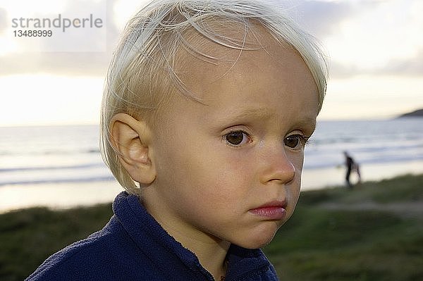 Kleiner Junge  der traurig auf einer Düne am Meer steht  Bretagne  Frankreich  Europa