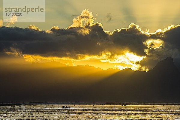 Silhouette von Kajakfahrern  Sonnenstrahlen brechen durch die Wolken über Moorea  Papeete  Tahiti