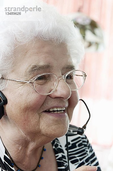 Ältere Frau am Telefon  sehr zufrieden  während sie zum ersten Mal ein Headset benutzt  Deutschland  Europa