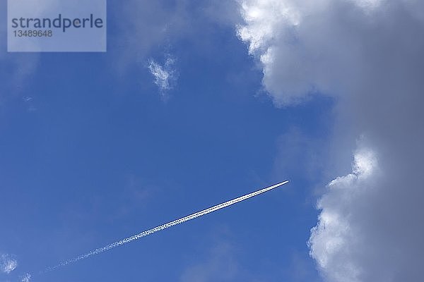 Flugzeug mit Kondenswasserstreifen im blauen Wolkenhimmel  Deutschland  Europa
