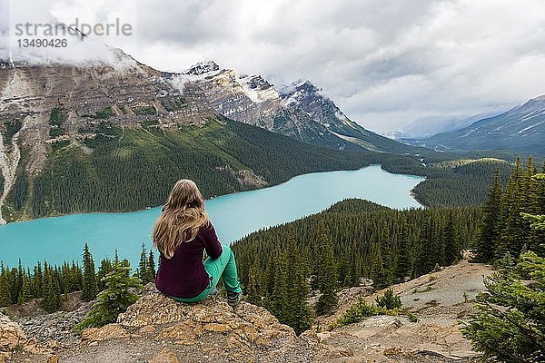 Junge Frau sitzt auf einem Stein und schaut in die Natur  türkisfarbener See  Peyto Lake  Rocky Mountains  Banff National Park  Provinz Alberta  Kanada  Nordamerika