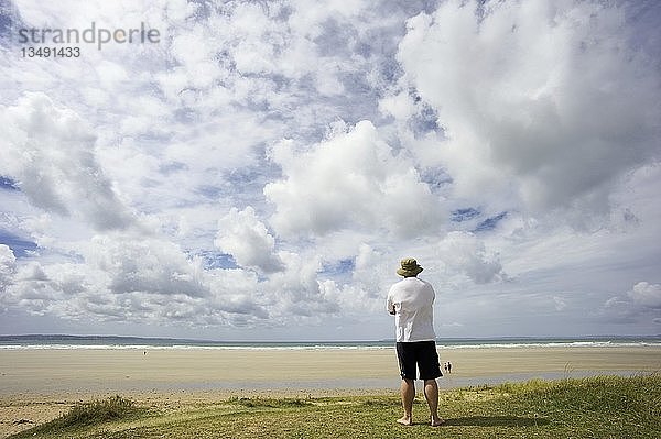 Ein Mann auf einer Düne mit Blick auf das Meer  Bretagne  Frankreich  Europa