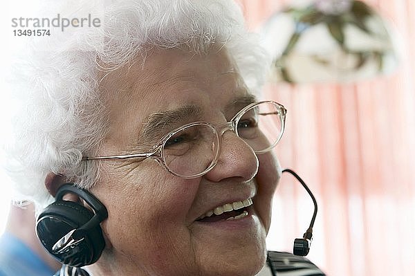 Ältere Frau am Telefon  sehr zufrieden  während sie zum ersten Mal ein Headset benutzt  Deutschland  Europa