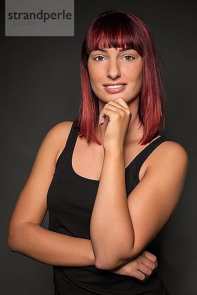 Junge Frau mit roten Haaren  posierend  in die Kamera schauend