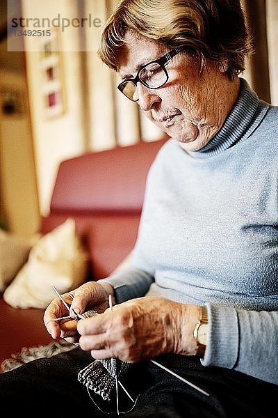 Seniorin strickt zu Hause auf dem Sofa einen Strumpf  Nordrhein-Westfalen  Deutschland  Europa