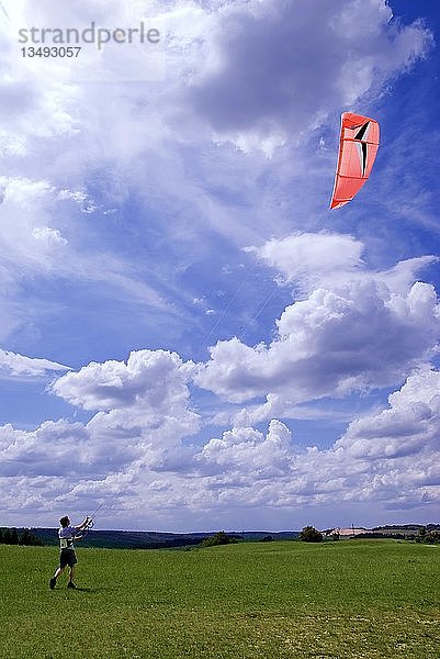 Mann lässt einen Drachen in einem bewölkten blauen Himmel steigen