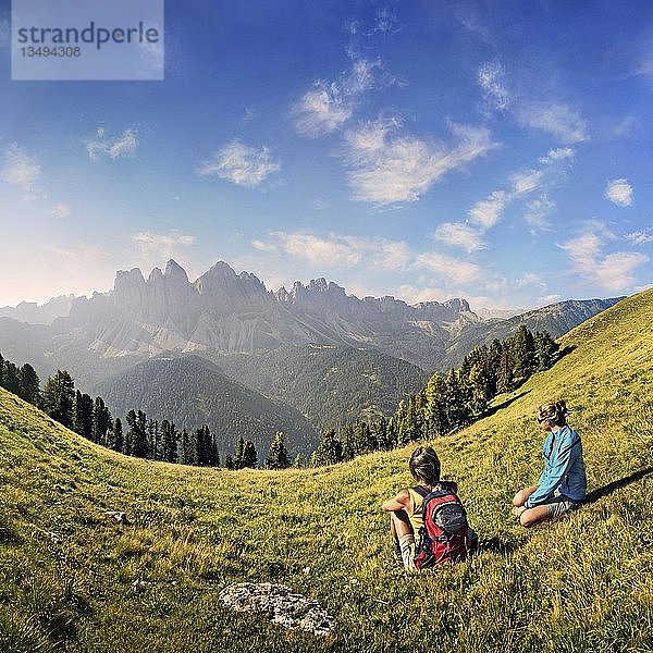 Wanderer ruhen sich auf einer Wiese aus und genießen die Aussicht auf die Geislergruppe  Aferer Geisler  Villnösstal  Provinz Bozen  Italien  Europa