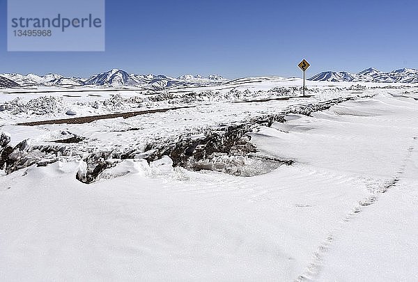 Schneebedeckte Straße durch die Atacama-Wüste mit Straßenschild vor den Anden  Altiplano  Bolivien  Südamerika
