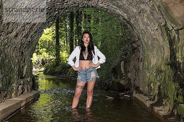 Junge asiatische Frau posiert im Wasser mit Hotpants  Mode