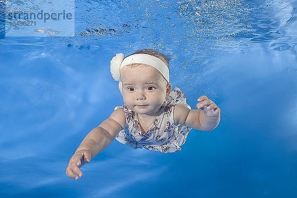 Kleines Mädchen in einem Kleid schwimmt unter Wasser im Pool  Odessa  Ukraine  Europa