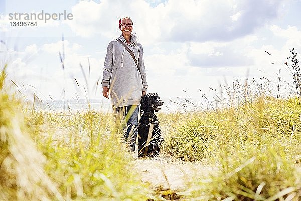 Frau geht mit ihrem Hund  Königspudel  in den Dünen am Meer spazieren  Portbail  Normandie  Frankreich  Europa