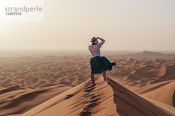 Junge Frau beim Fotografieren in der Ferne  rote Sanddüne in der Wüste  Dünenlandschaft Erg Chebbi  Merzouga  Sahara  Marokko  Afrika